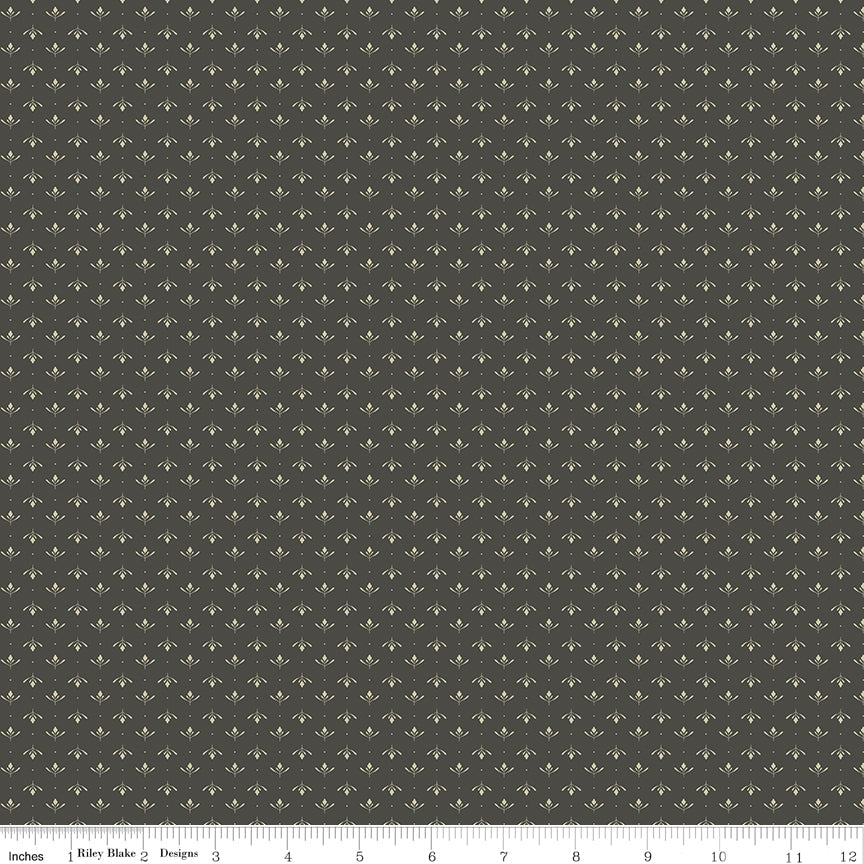 Lottie Gray fabric with tiny cream leaf sprigs and dots in alternating rows on a dark warm gray background with ruler for scale.
