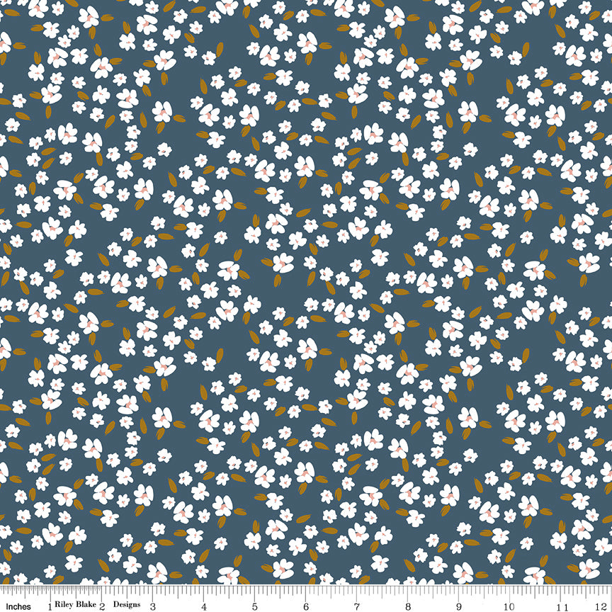 Blossoms Blue fabric with white flowers, blush centers, and ochre leaves on a deep slate-blue background with ruler for scale.