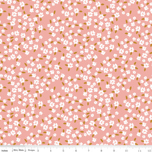 Blossoms Coral fabric with scattered white flowers and golden ochre leaves on a coral-pink background with ruler for scale.