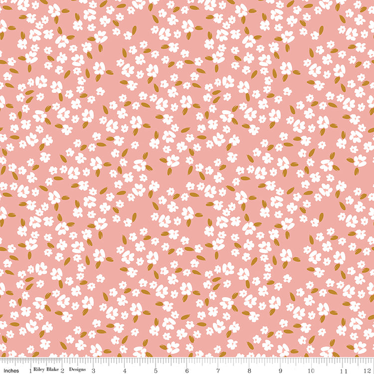 Blossoms Coral fabric with scattered white flowers and golden ochre leaves on a coral-pink background with ruler for scale.