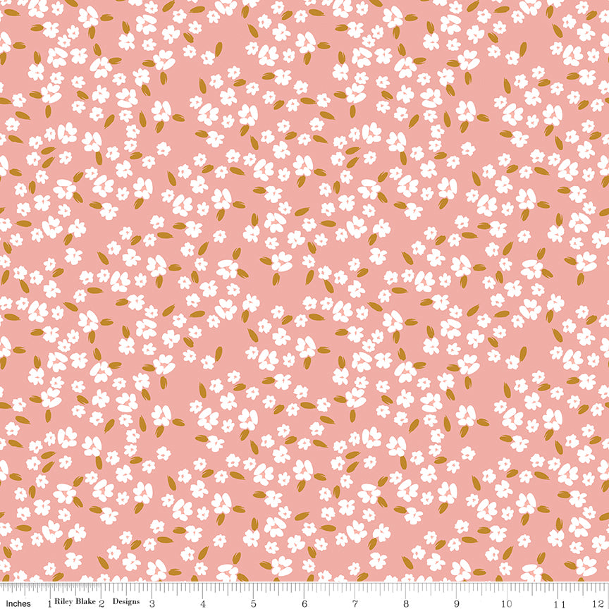 Blossoms Coral fabric with scattered white flowers and golden ochre leaves on a coral-pink background with ruler for scale.