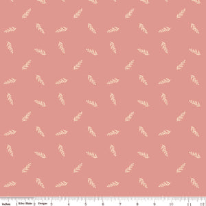 Toss Coral fabric with small cream leafy sprigs tossed across a muted coral-pink background with ruler for scale.