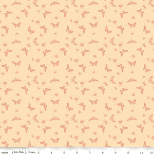 Flutter Blush fabric with coral butterflies, moths, bees, and other insects on a pale peach background with ruler for scale.