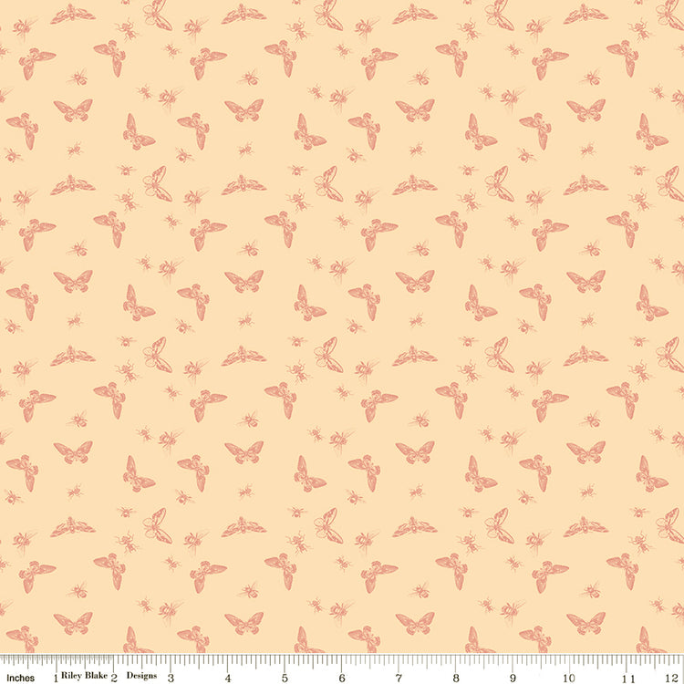 Flutter Blush fabric with coral butterflies, moths, bees, and other insects on a pale peach background with ruler for scale.