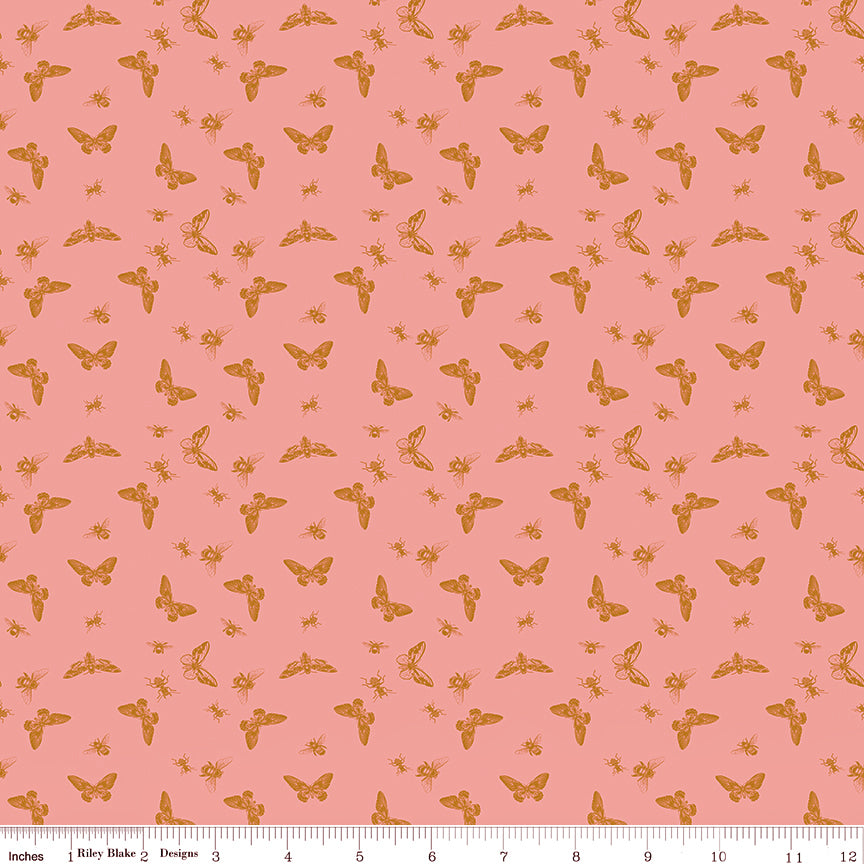 Flutter Coral fabric with golden ochre butterflies, moths, and small insects on a coral-pink background with ruler for scale.