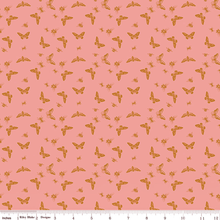 Flutter Coral fabric with golden ochre butterflies, moths, and small insects on a coral-pink background with ruler for scale.