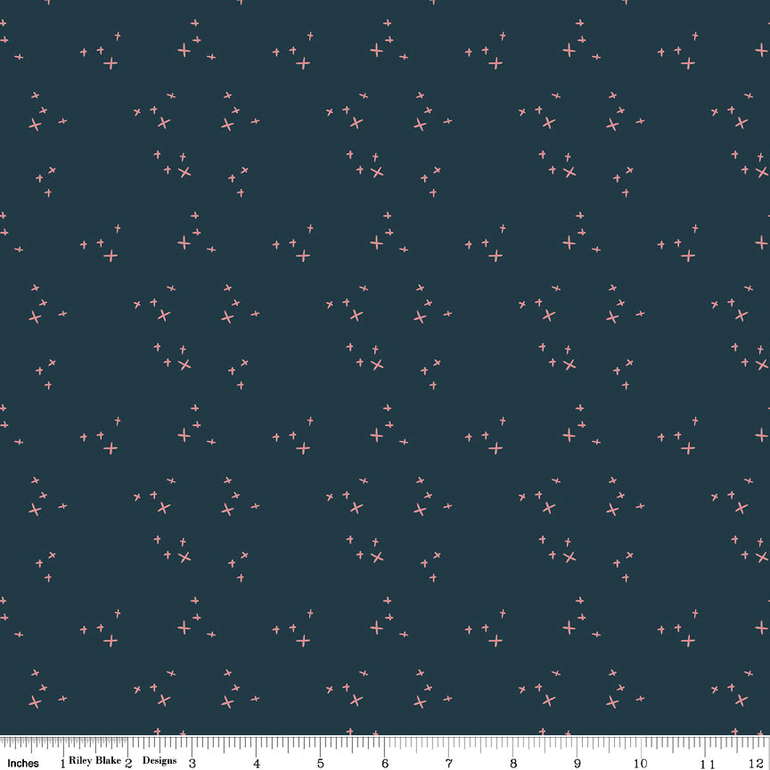 Scatter Blue fabric with small coral-pink crosses in loose clusters on a deep teal-blue background with ruler for scale.