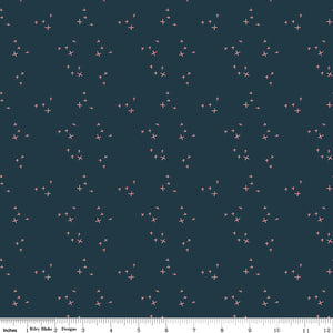 Scatter Blue fabric with small coral-pink crosses in loose clusters on a deep teal-blue background with ruler for scale.