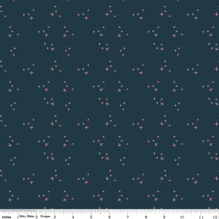 Scatter Blue fabric with small coral-pink crosses in loose clusters on a deep teal-blue background with ruler for scale.