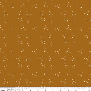 Scatter Butterscotch fabric with scattered cream crosses on a warm golden ochre background with ruler for scale.