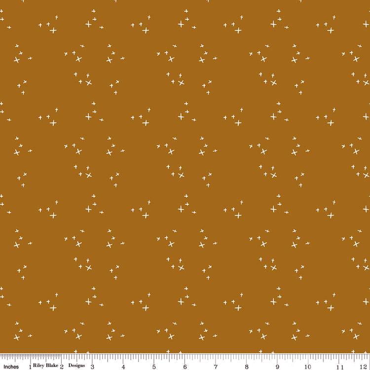Scatter Butterscotch fabric with scattered cream crosses on a warm golden ochre background with ruler for scale.