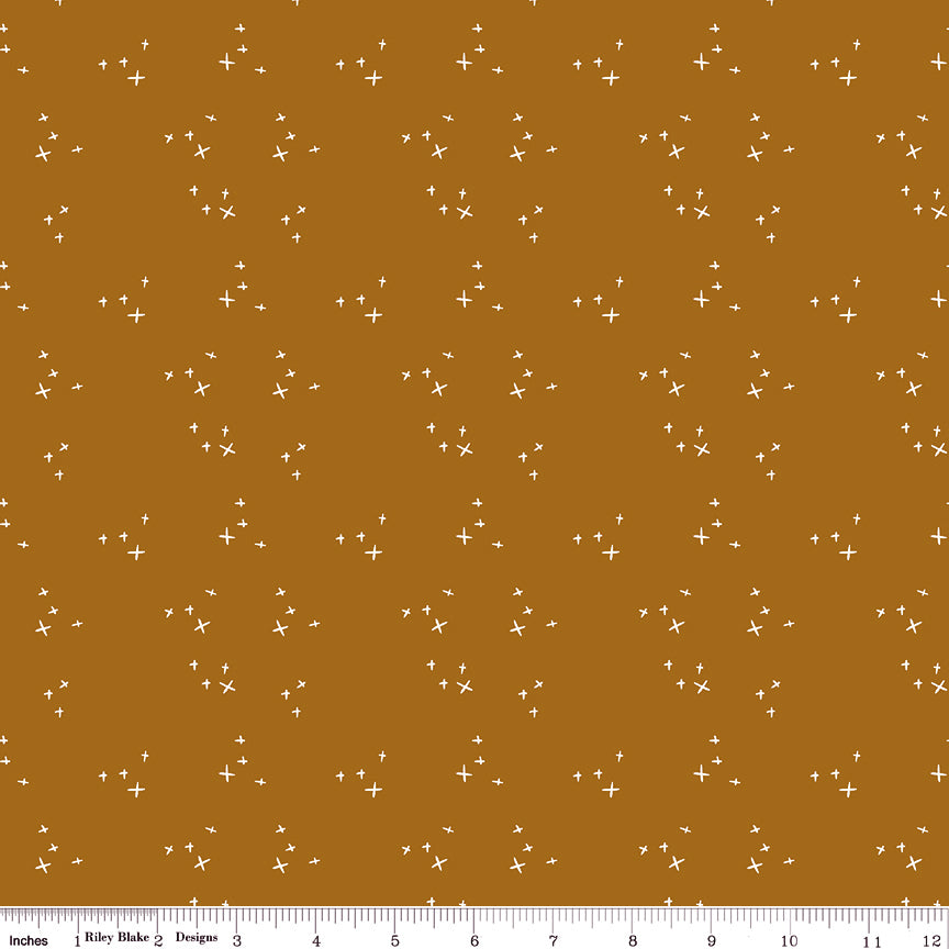 Scatter Butterscotch fabric with scattered cream crosses on a warm golden ochre background with ruler for scale.