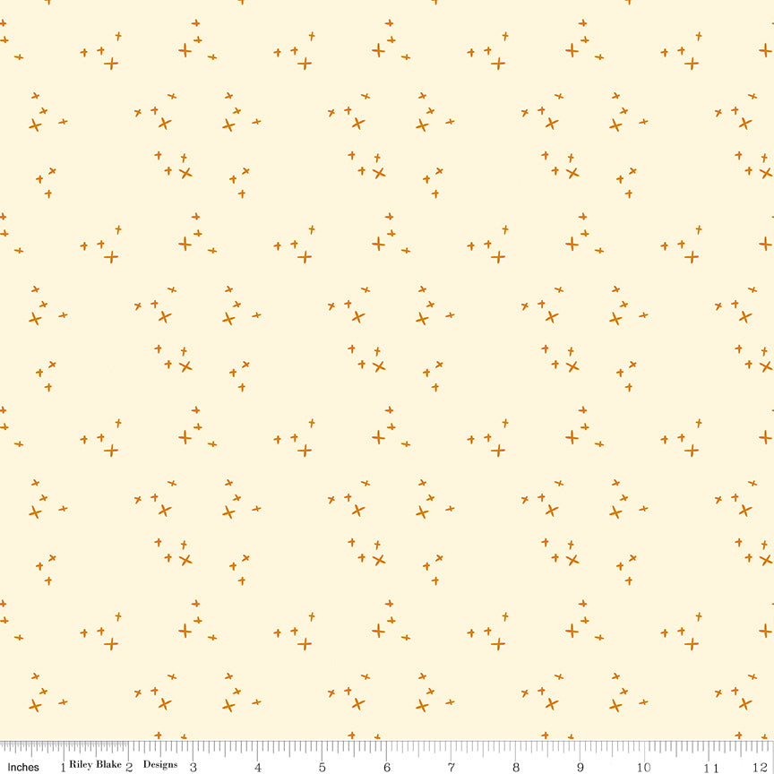 Scatter Cream fabric with small golden-orange crosses arranged in loose clusters on a pale cream background with ruler for scale.