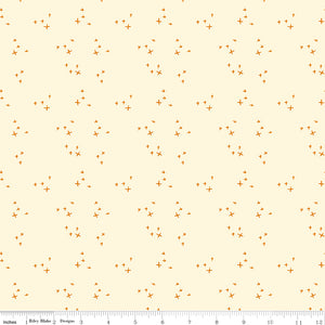Scatter Cream fabric with small golden-orange crosses arranged in loose clusters on a pale cream background with ruler for scale.
