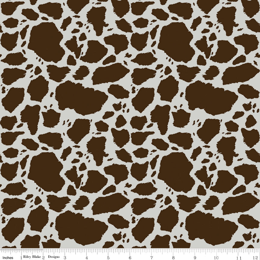Cow Patches Brown fabric with chocolate brown cowhide-style markings on an off-white background with ruler for scale.