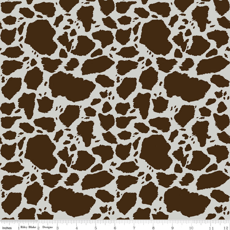 Cow Patches Brown fabric with chocolate brown cowhide-style markings on an off-white background with ruler for scale.