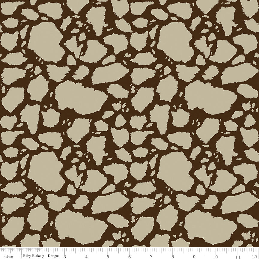 Cow Patches Tan fabric with sandy tan cowhide-style patches on a deep brown background with ruler for scale.