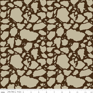 Cow Patches Tan fabric with sandy tan cowhide-style patches on a deep brown background with ruler for scale.