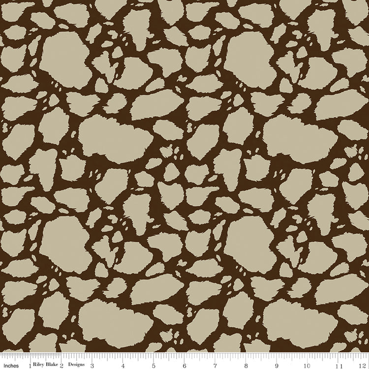 Cow Patches Tan fabric with sandy tan cowhide-style patches on a deep brown background with ruler for scale.