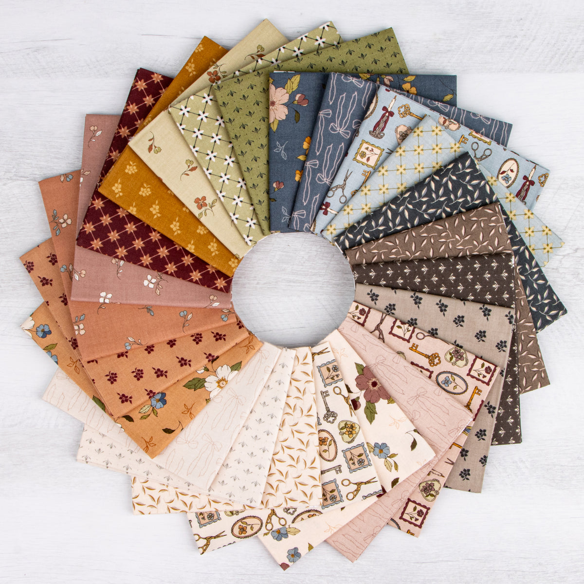 A circular arrangement of multiple fabric swatches in assorted earthy patterns and colors, including rust, sage, navy, beige, and brown, displayed on a white wood background.