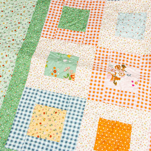 Close-up of a Cotton Nook quilt with floral blocks, gingham borders and decorative quilting.