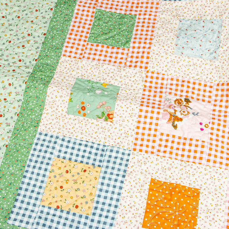 Close-up of a Cotton Nook quilt with floral blocks, gingham borders and decorative quilting.