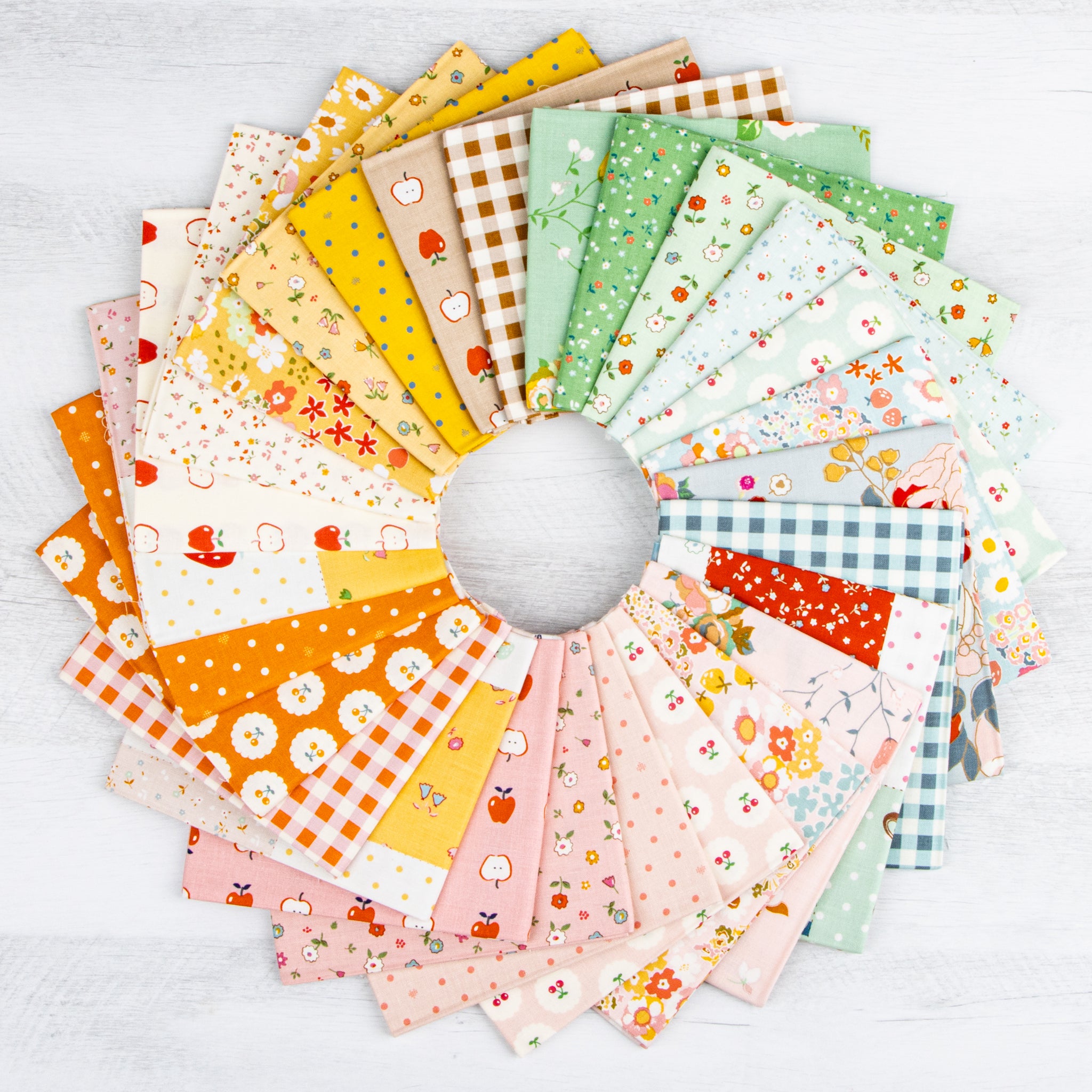 Cotton Nook fabric collection arranged in a colorful fan of florals, fruit, dots and ginghams.