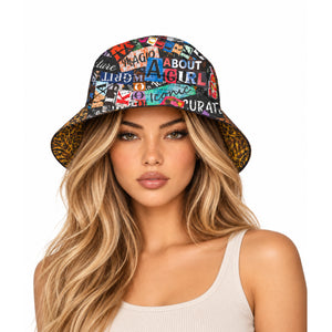 A woman with long blonde hair wearing a bucket hat with a colorful collage print and leopard-print brim, paired with a white ribbed tank top, against a solid white background.