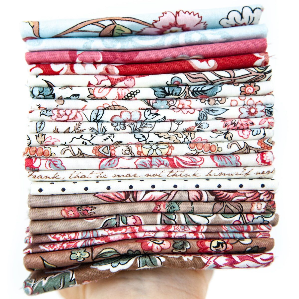 A hand holding a stack of folded patterned fabric pieces in various colors and designs, including floral, paisley, and striped motifs.
