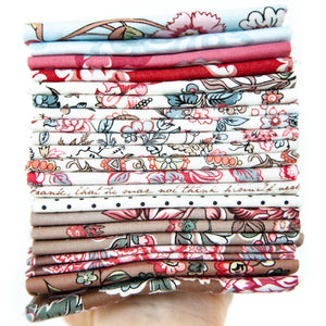A hand holding a stack of folded patterned fabric pieces in various colors and designs, including floral, paisley, and striped motifs.