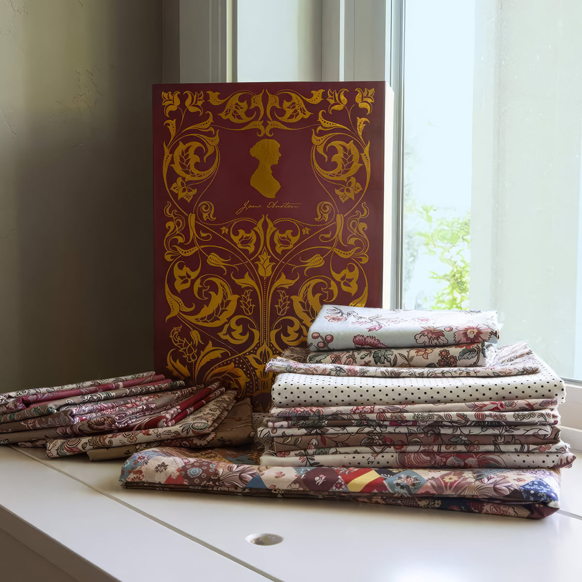 Stack of fabric swatches on a table with an ornate book in the background