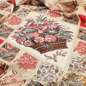 A close-up of a fabric featuring a patchwork design with floral motifs, peonies, and a central basket bouquet print in muted red, pink, beige, brown, and gray tones.