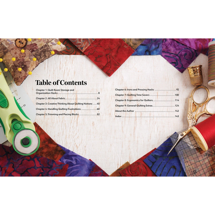 A tabletop flat-lay showing a printed book or booklet page titled 'Table of Contents' placed over a quilted fabric background with sewing tools around it, including scissors, thread, pins, and a thimble.