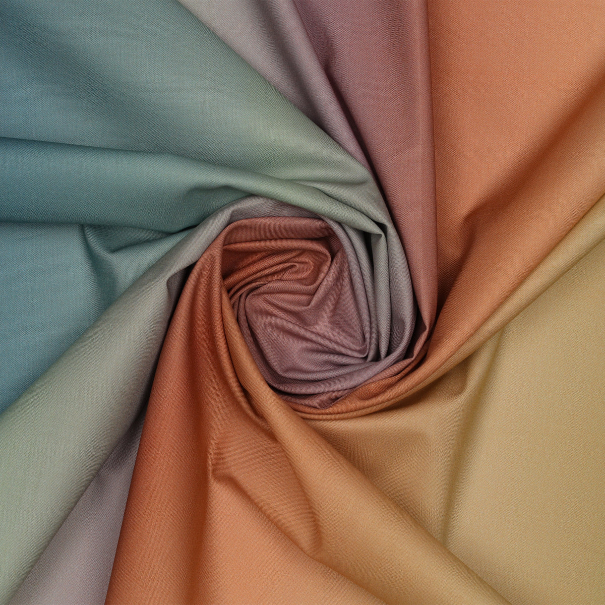 Shades of Sky Ombre fabric draped in a spiral, showcasing blended shades of teal, sage, mauve, terracotta, and warm gold.