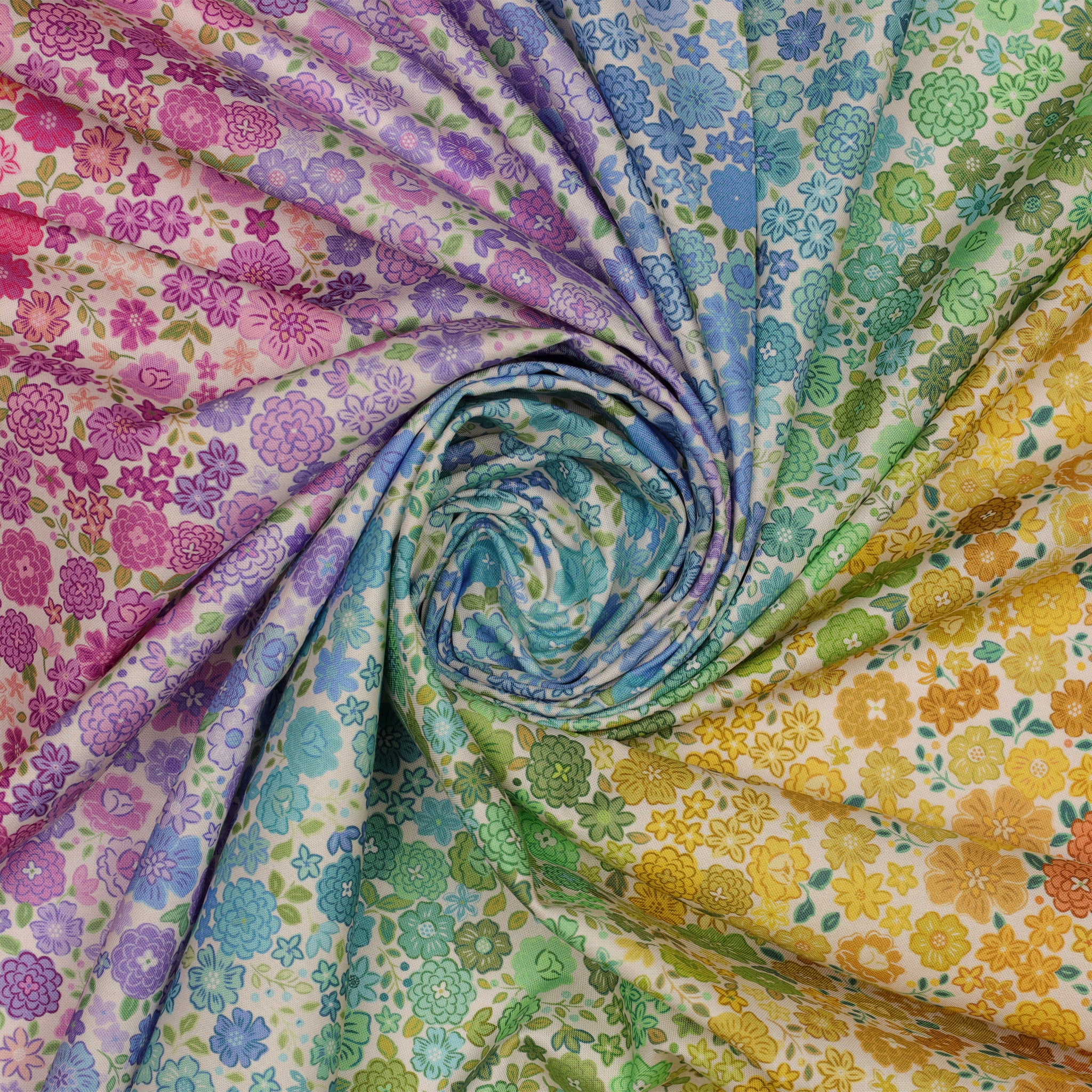 Pastel Boho Blooms Ombre fabric draped in a spiral with pastel rainbow flowers and green leafy accents.