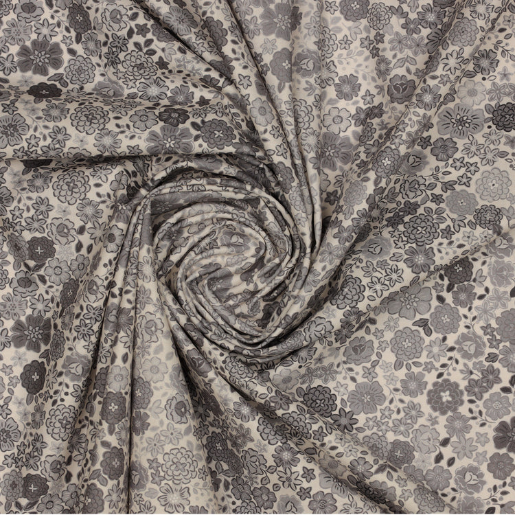 Gray floral fabric with assorted blossoms and leaves, gathered into a spiral.
