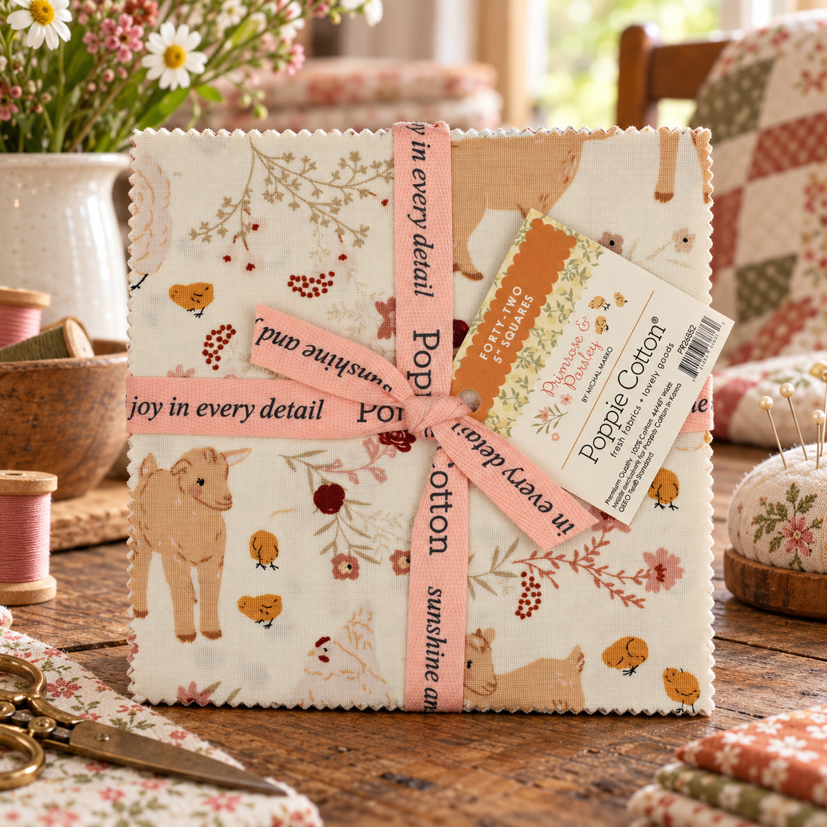 Fabric bundle wrapped with a pink ribbon displayed on a wooden table with sewing props and floral textiles in the background.