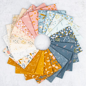A circular arrangement of patterned fabric swatches in soft pastel and earthy tones, including pink, blue, mustard yellow, cream, and gray floral and leaf prints, displayed on a light textured background.