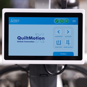 A Grace QuiltMotion X digital control screen mounted on a sewing machine, showing the user interface with options for jog directions and stitch settings.