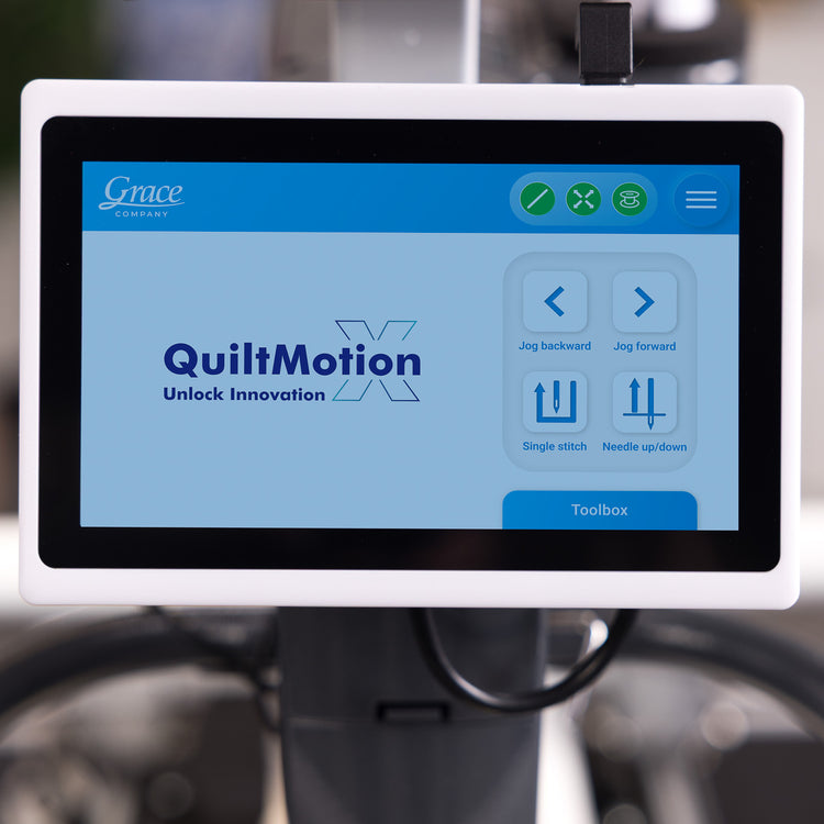 A Grace QuiltMotion X digital control screen mounted on a sewing machine, showing the user interface with options for jog directions and stitch settings.
