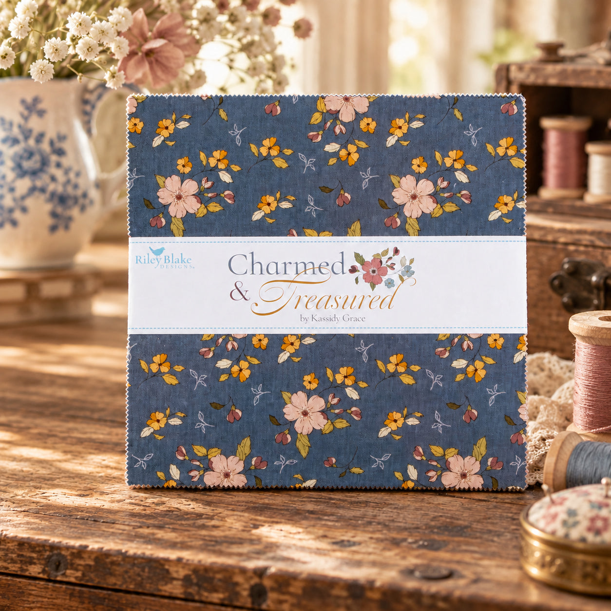 A fabric bundle with a blue floral pattern bound by a white paper band sits on a rustic wooden table.