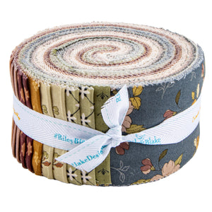 A roll of layered fabric cut pieces tied with a white ribbon printed with the text 'Riley Blake Designs', shown on a plain white background.