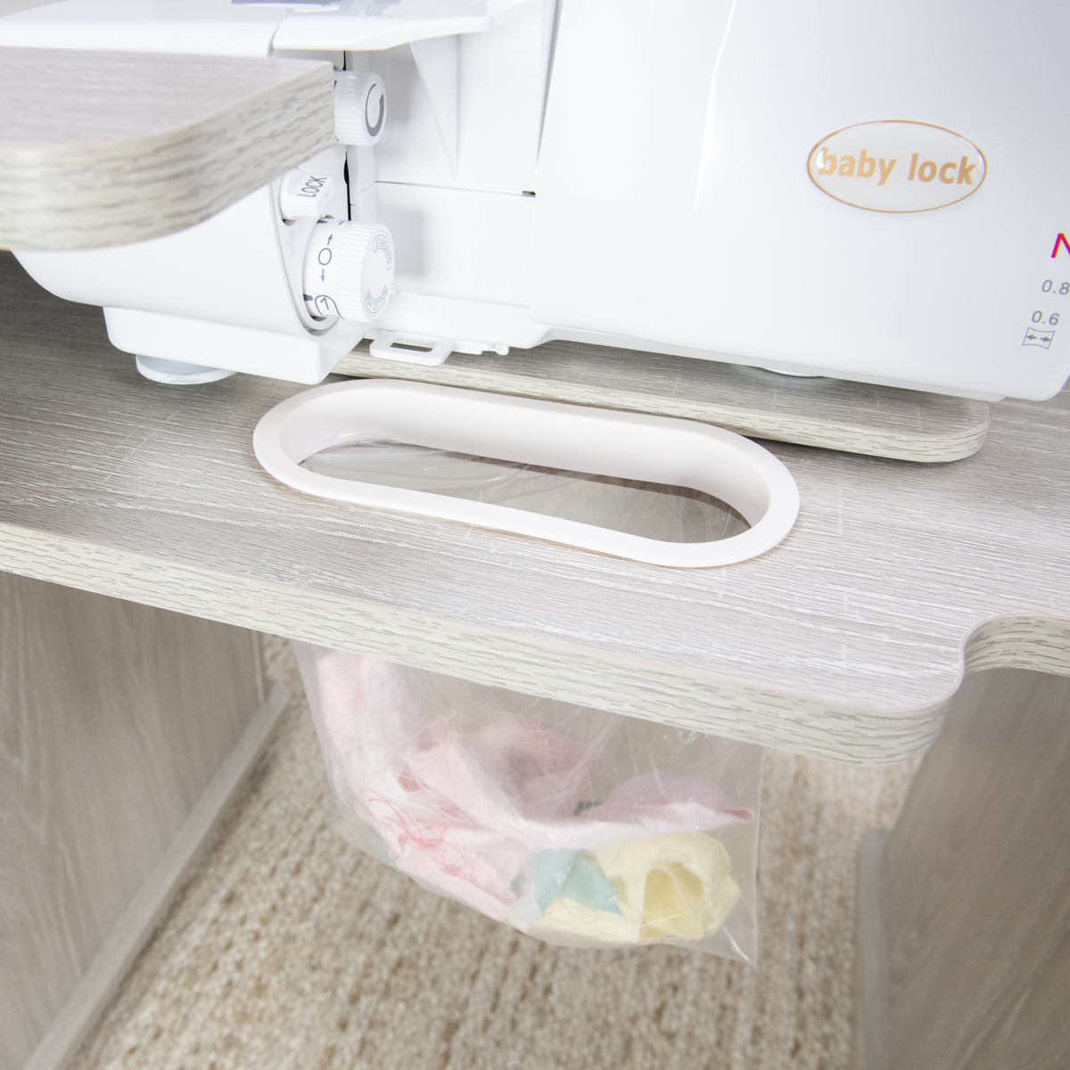 Koala Serger Studio cabinet built-in trash chute below a Baby Lock serger for catching thread waste
