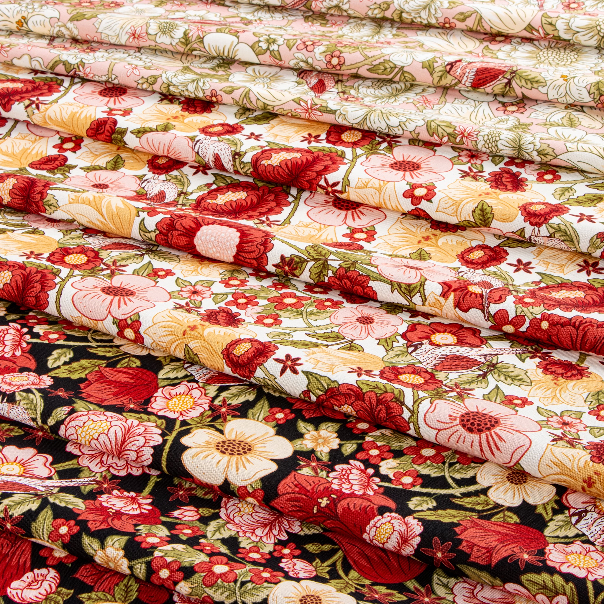 Layered floral fabrics in cream, pink, red, green, and black with birds and garden blooms.