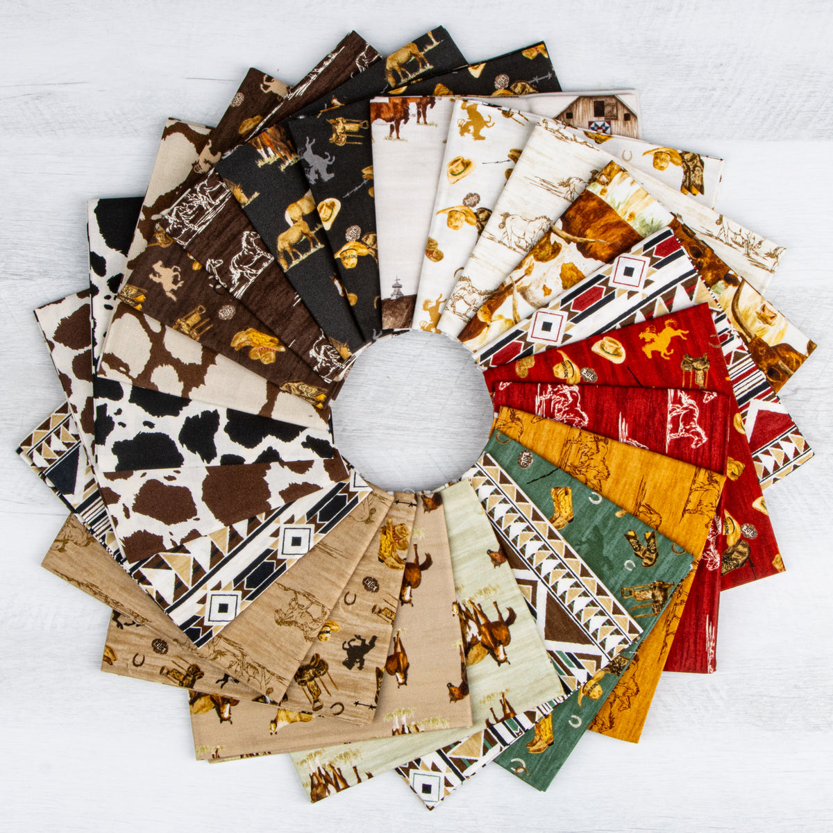 A circular arrangement of multiple fabric squares with western and animal-themed prints, including cow spots, horses, and geometric patterns, displayed on a white wood background.