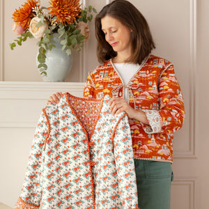 Woman displaying a floral quilted jacket beside an autumn Village Life jacket.