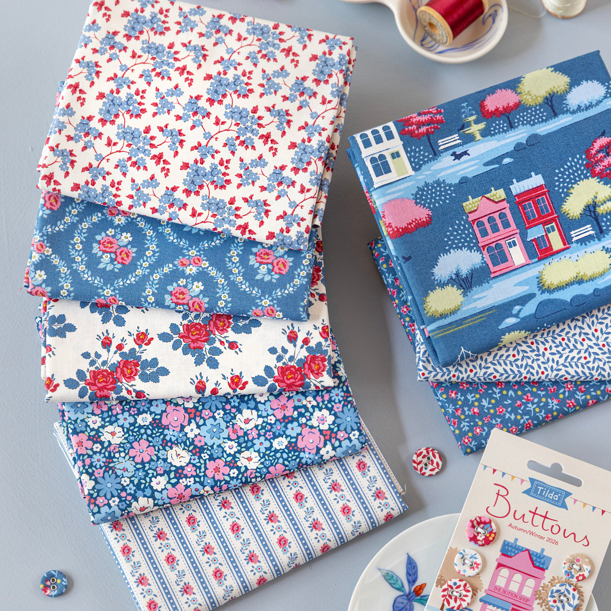 Folded Village Life fabrics in blue, red and cream floral and village patterns.