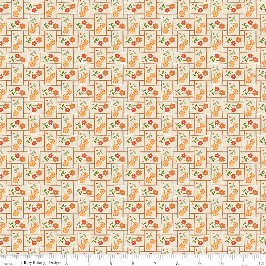 Small orange flowers with green leaves on a patchwork pattern with a ruler along the bottom for scale. 