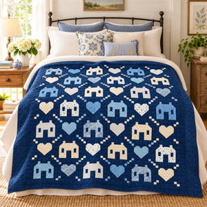 Friendly Neighborhood quilt in blue and cream colorway styled on a cozy bedroom bed.