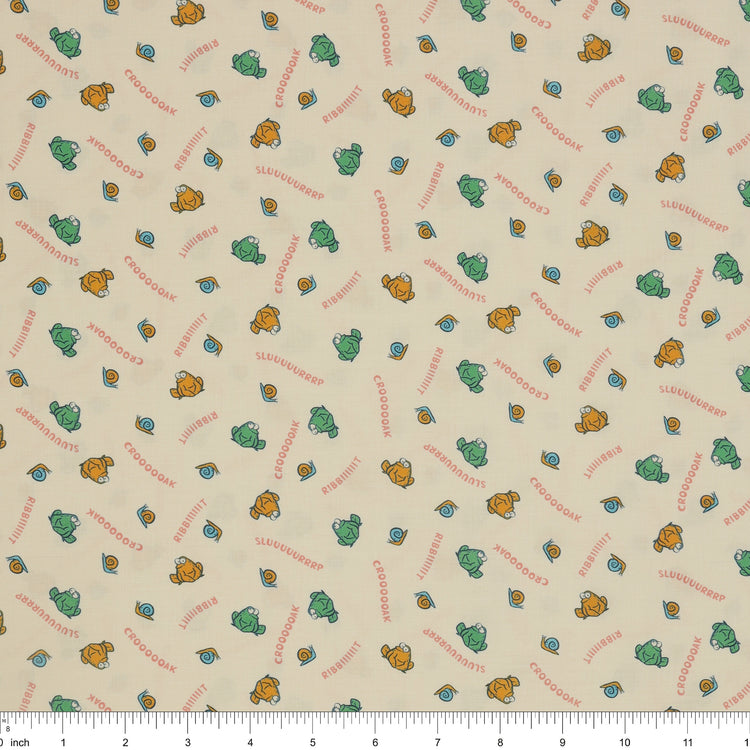 Toadally Chatty Cream fabric with green and yellow frogs, tiny snails, and coral sound words with ruler for scale.